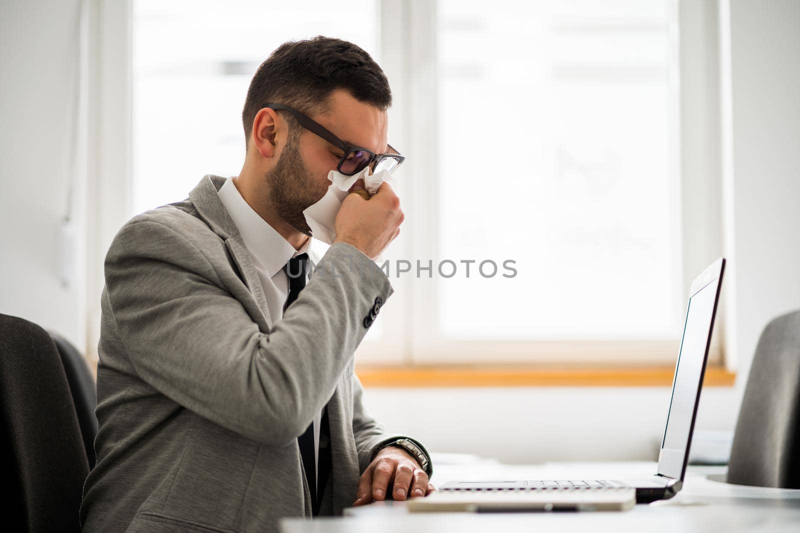 Young businessman is working in office. He is having cold.