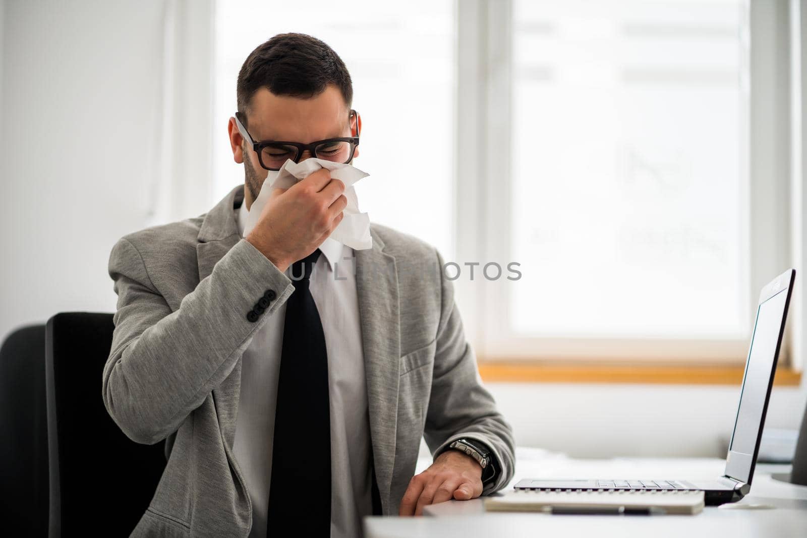 Young businessman is working in office. He is having cold.