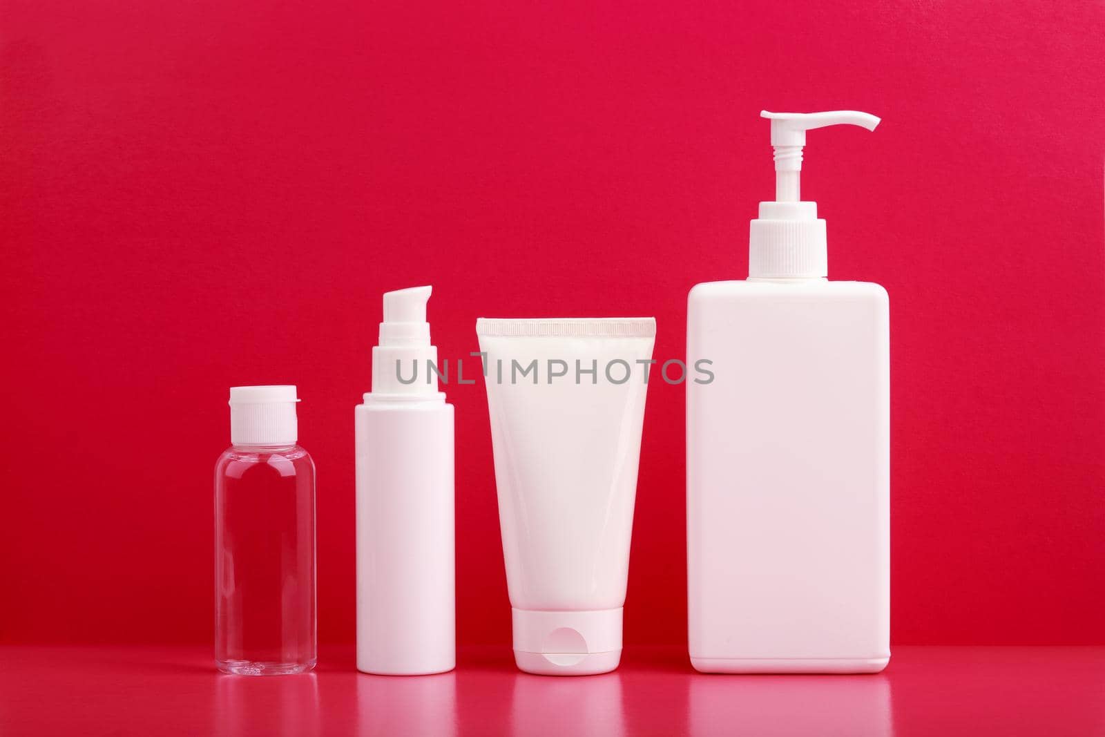 Set of cosmetic for skin care in white tubes on pink table against bright pink background. Concept of beauty treatment and skin care products for daily skin cleaning and moisturizing