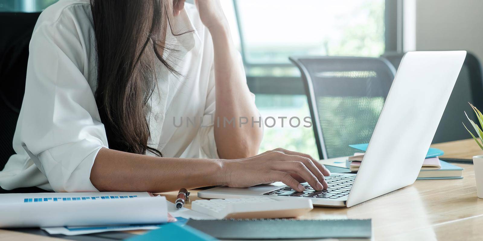 Close-up image of young professional female manager using laptop at her office, businesswoman working from home.