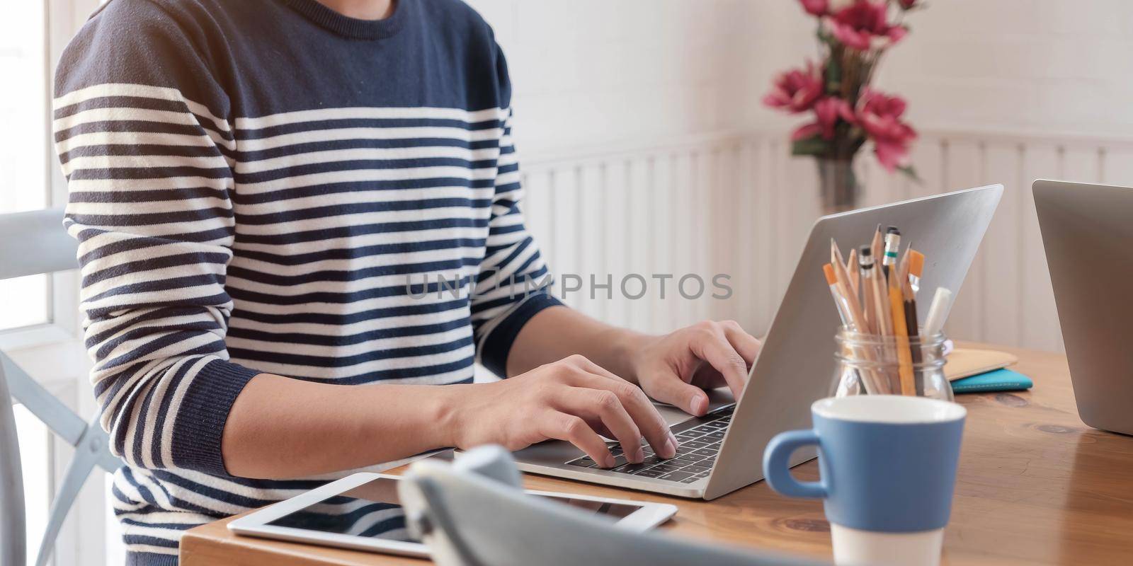 Close-up image of young professional male manager using laptop at he office, businessman working from home via portable computer by wichayada