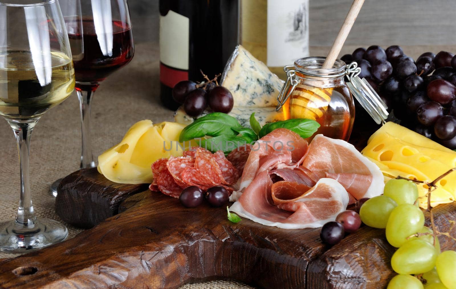 Antipasto catering platter with jerky bacon,  prosciutto, salami, cheese    and grapes on a wooden background