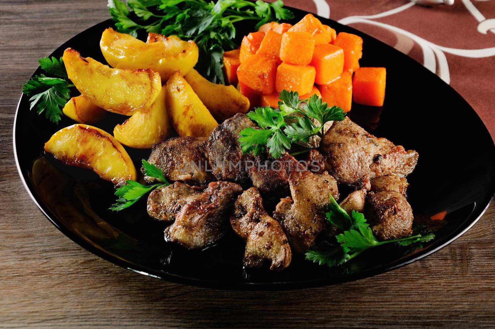Fried chicken liver with vegetable garnish, baked pumpkin and apple. 