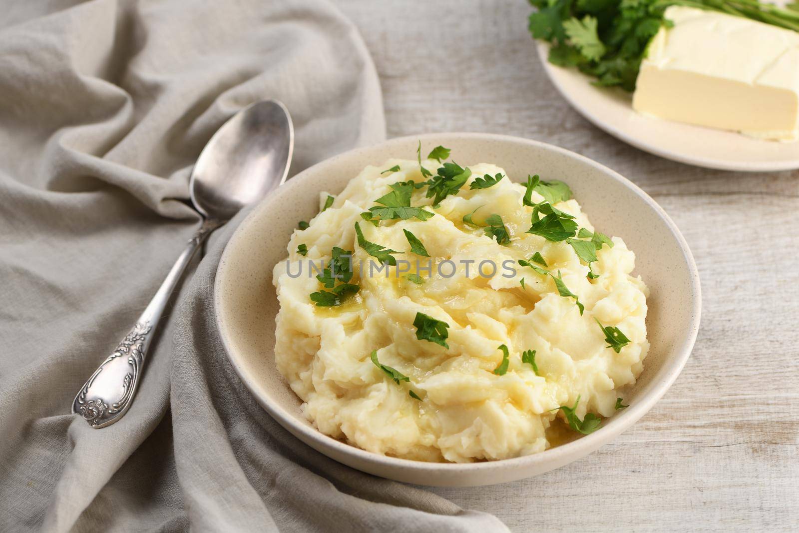 A plate of mashed potatoes poured with melted butter and seasoned with greens