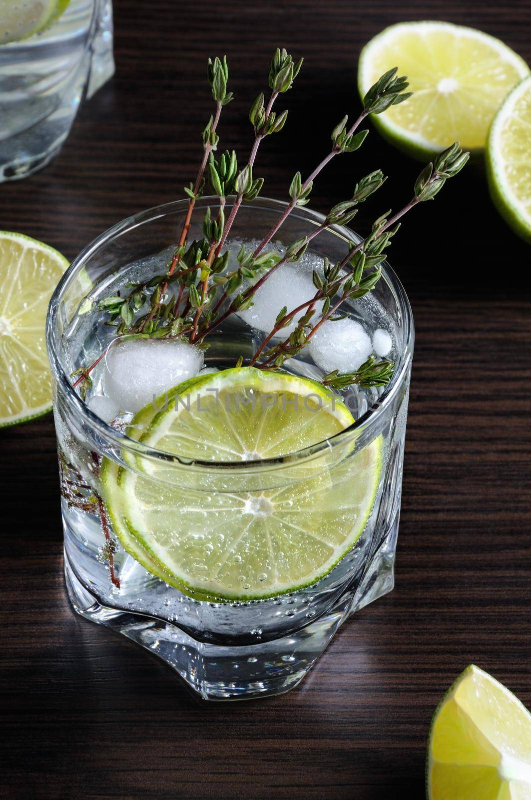 Cocktail with white rum and tonic, a slice of lime and thyme
