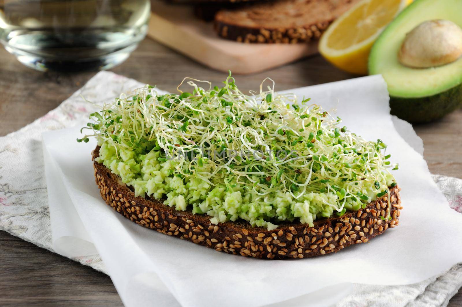 Sandwich of tender, juicy germinated alfalfa and avocado sprouts on slices of rye bread with cereals. This is a great idea for those who watch their health.