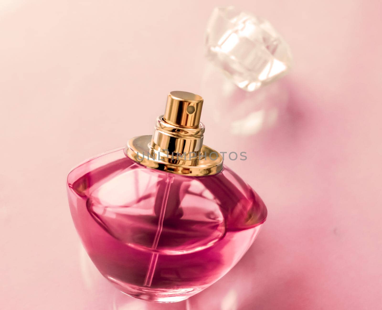 Perfumery, spa and branding concept - Pink perfume bottle on glossy background, sweet floral scent, glamour fragrance and eau de parfum as holiday gift and luxury beauty cosmetics brand design