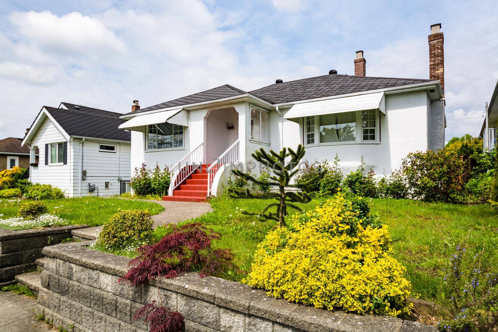 Main entrance of residential house with concrete pathway over green lawn on the front yard on cloudy day