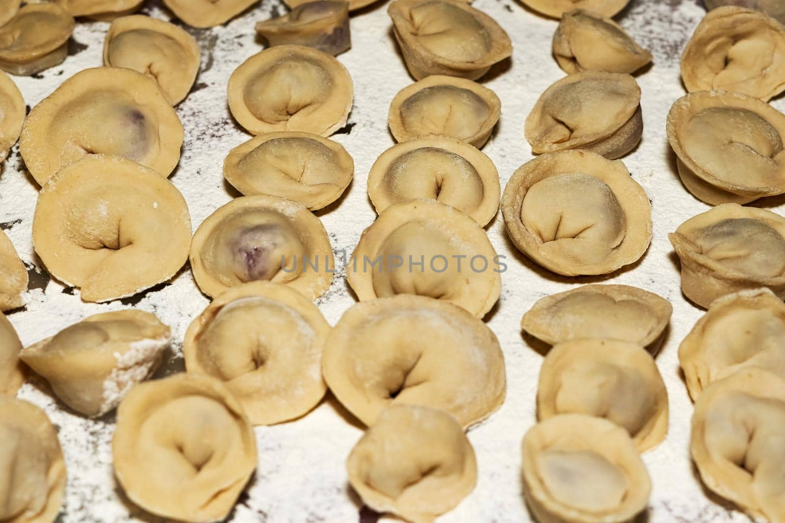 Raw dumplings with meat on the table sprinkled with white flour