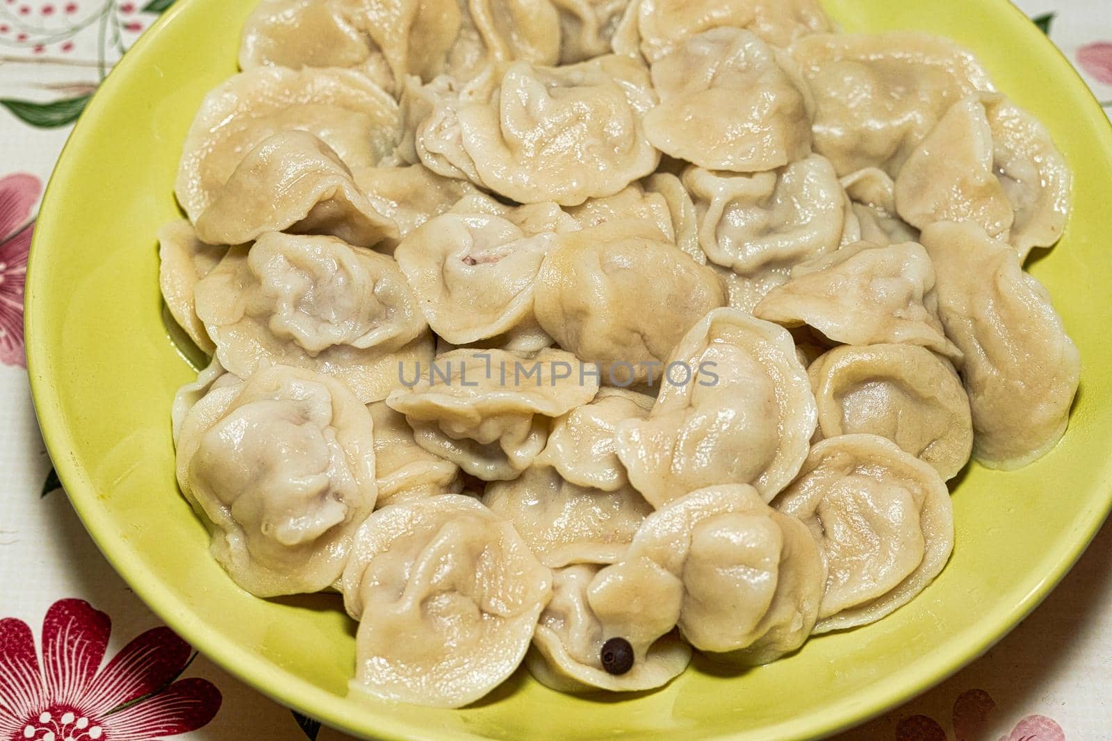 Cooked dumplings in a green plate on the dining table. Close up