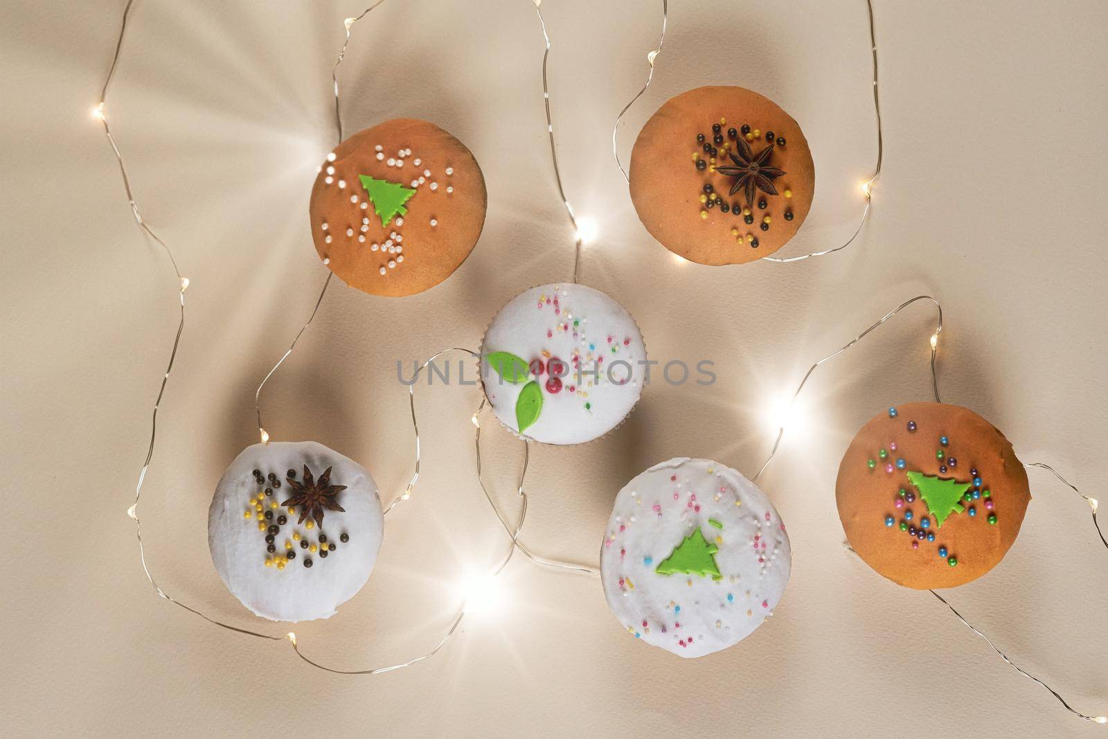 Muffins on a light background decorated for New Year and Christmas with a glowing garland, top view