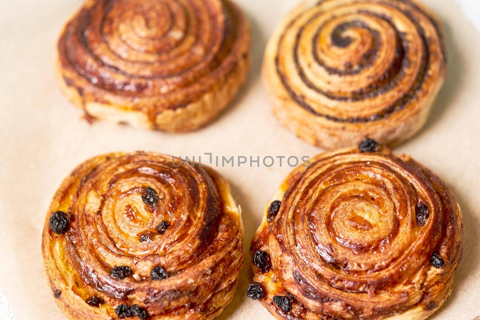 Fresh brown buns with raisins and poppy seeds on a light background close up