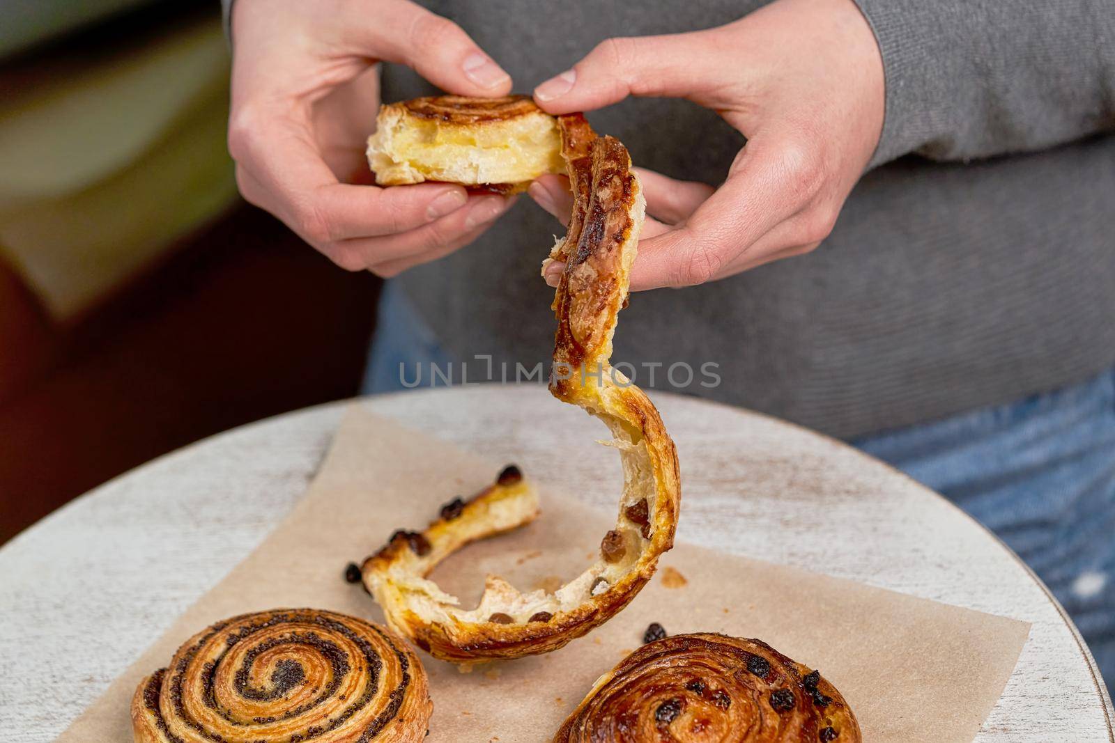 Hands tear off a piece of poppy seed roll. Chopping buns over the table by vizland