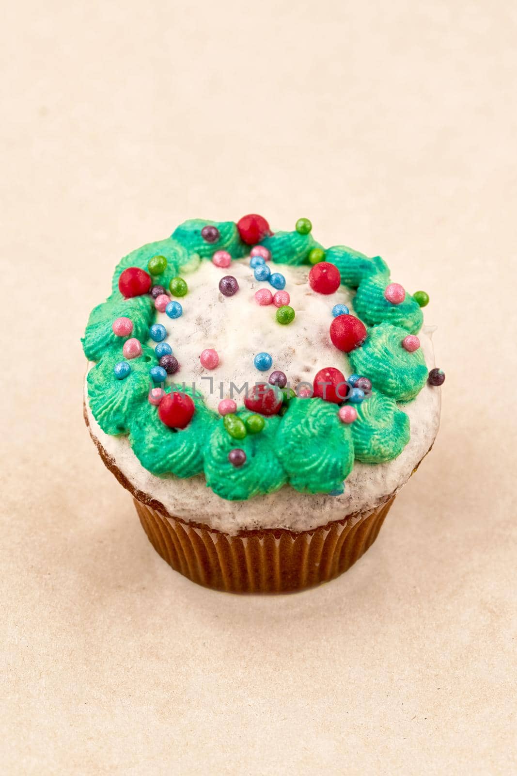 Chocolate muffin cake with light glaze and green cream. Close up on light background, vertical frame