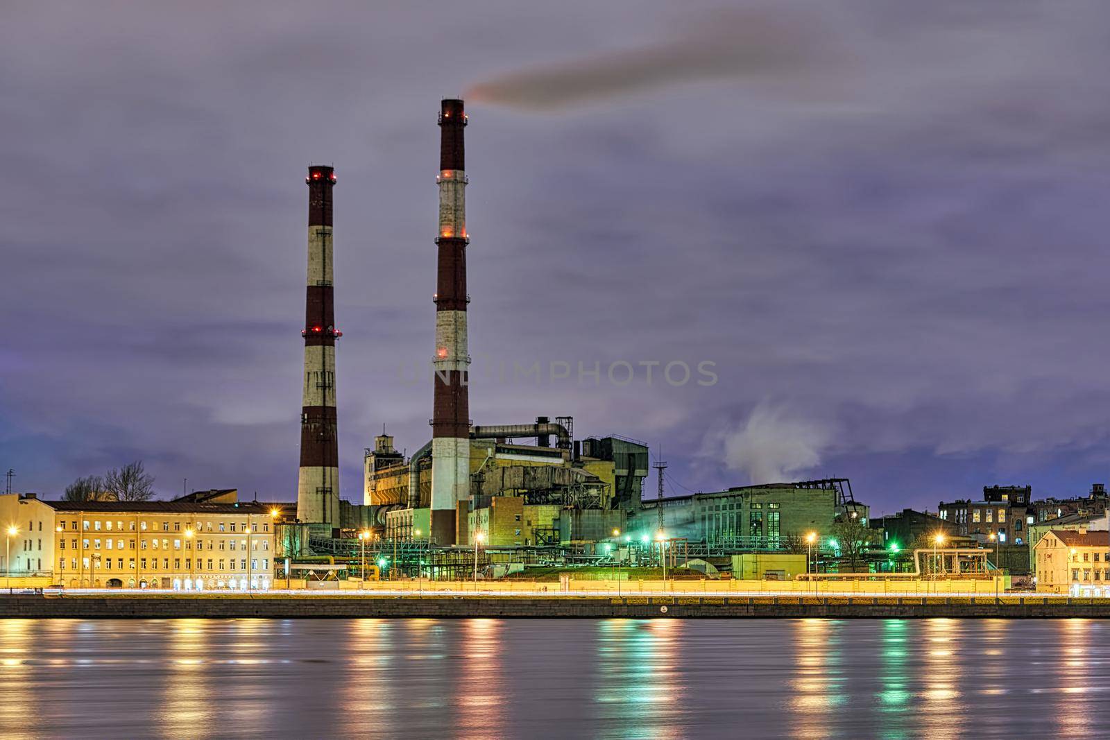 Tall smoking chimneys on the Sinop embankment of the Neva River. Russia, Saint Petersburg, night city landscape