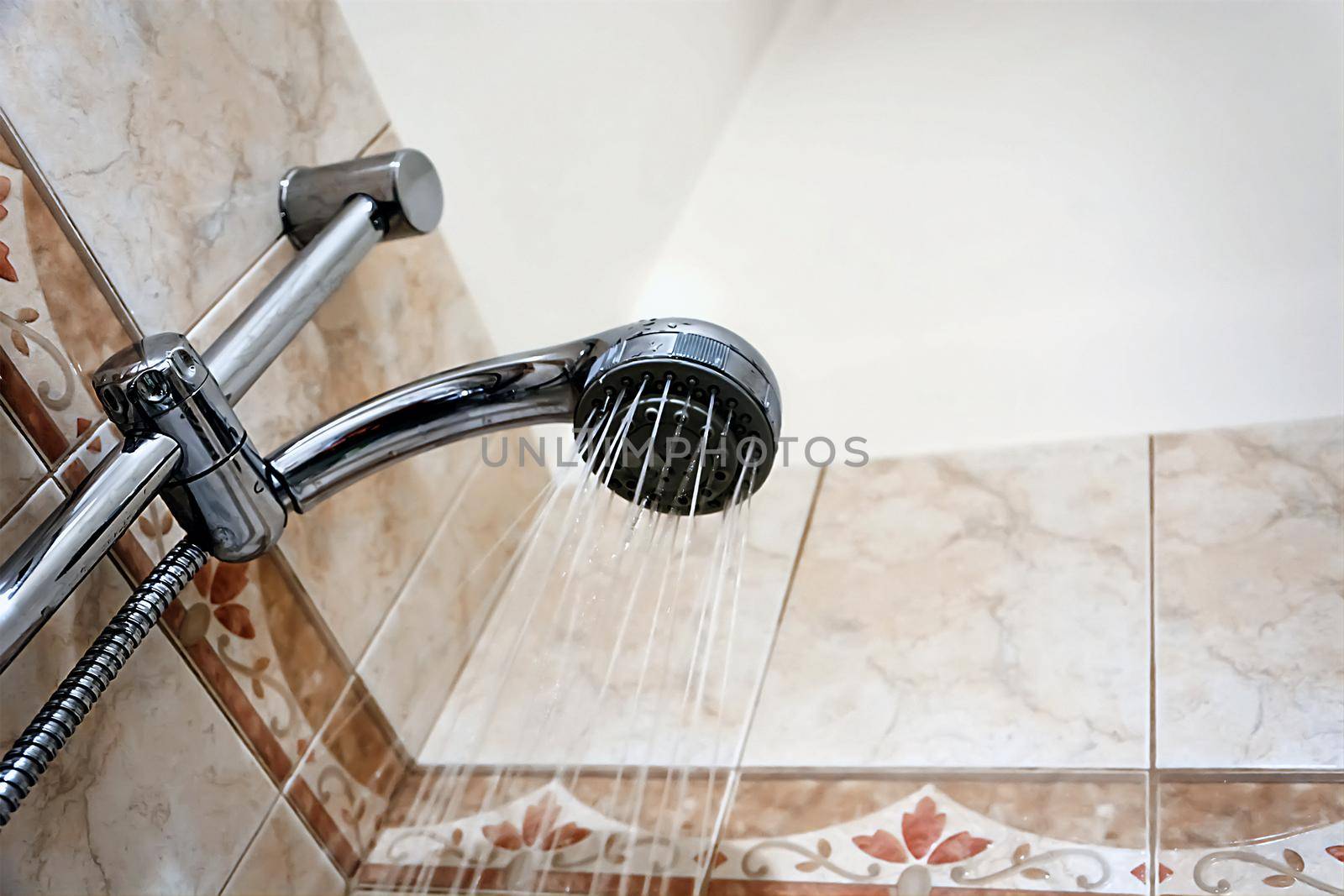 Interior of a shower with water flowing from the shower head. Droplets and moisture. Walls with decorated tiles. by rarrarorro