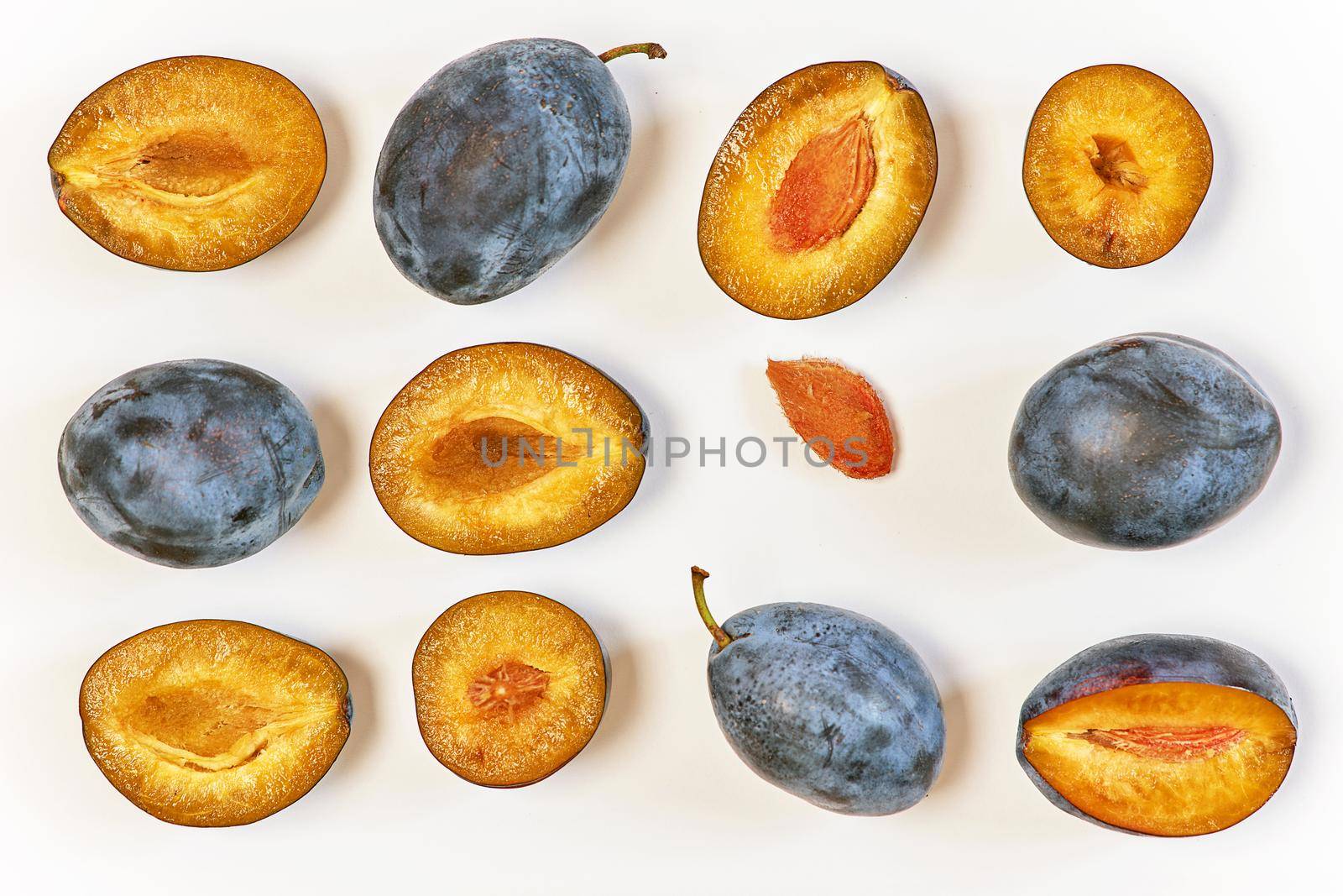 Ripe dark plums in various forms. Prunes on a light background, top view