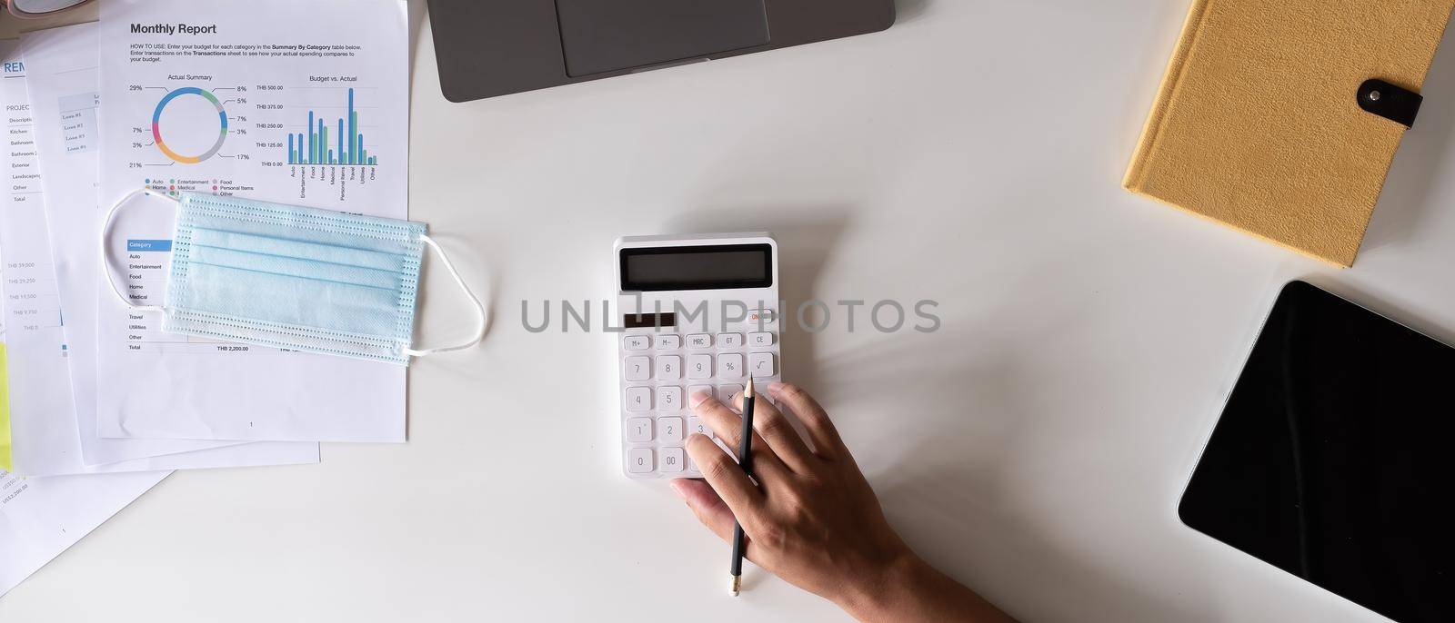 Top view hand of accountant using calculator on workplace, calculator and plant potted on white desk background, Accounting workplace concept by nateemee
