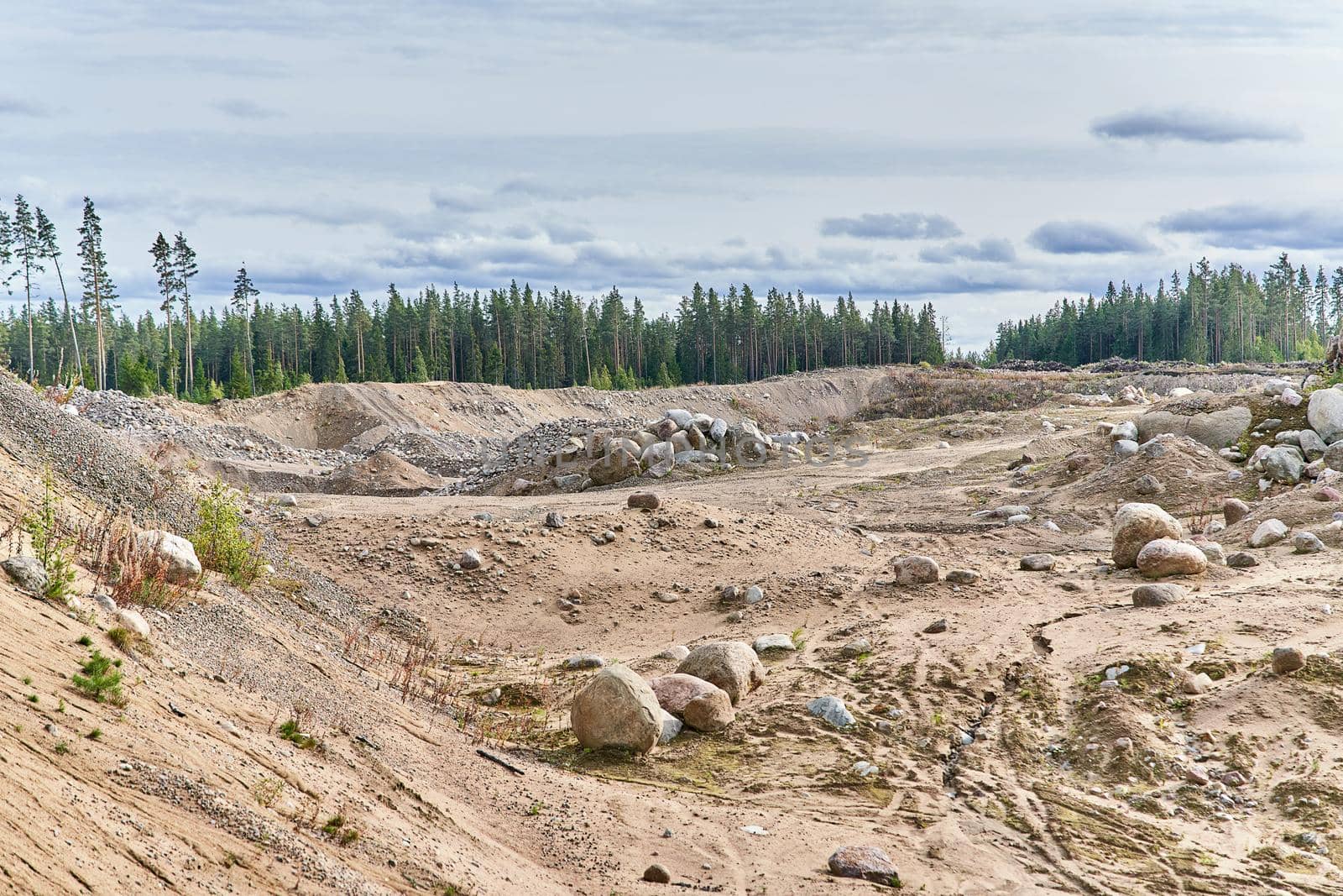 Quarry with sand and large stones against the background of the forest and sky by vizland