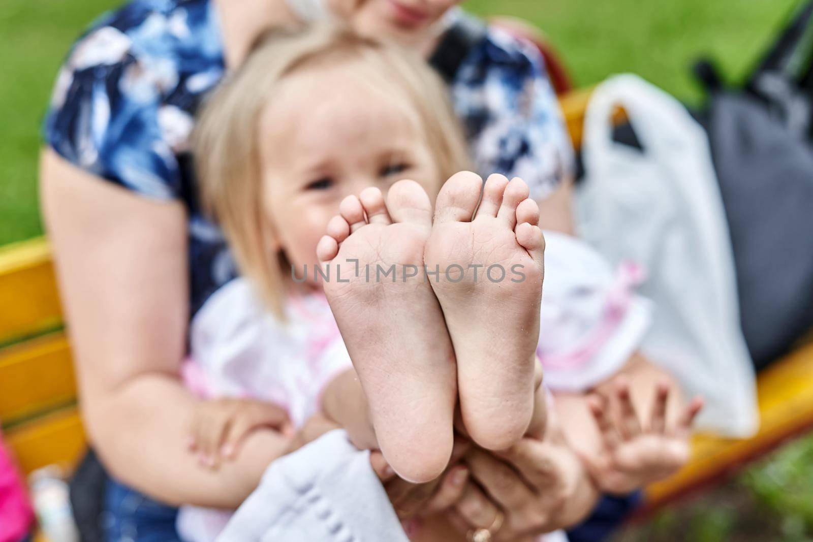 Girls bare feet close up. Mom changes shoes for the child