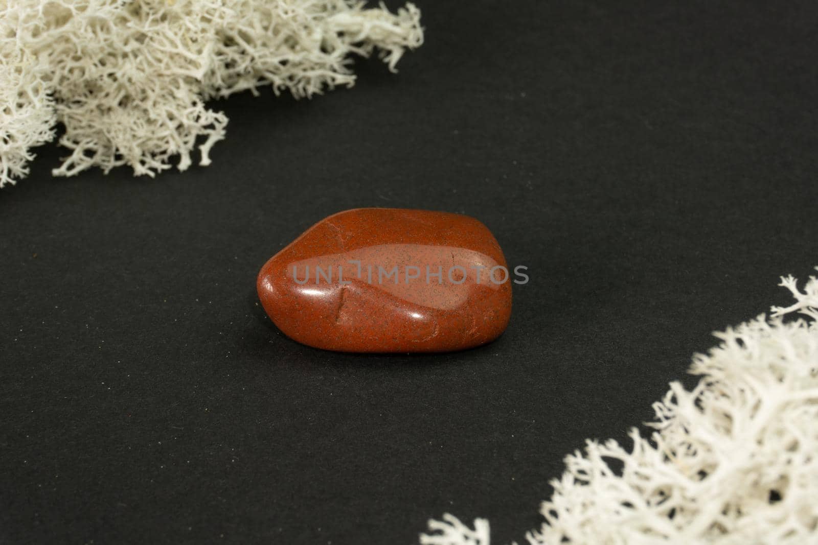 Red Jasper from Brazil. Natural mineral stone on black background. Mineralogy, geology, magic of stones, semi-precious stones and samples of minerals. Close-up macro photo.