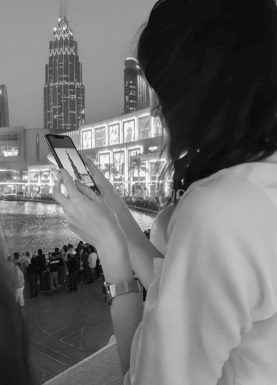 A girl takes photos on her mobile phone of the evening landscape with the sights of the city . Black and white photo.