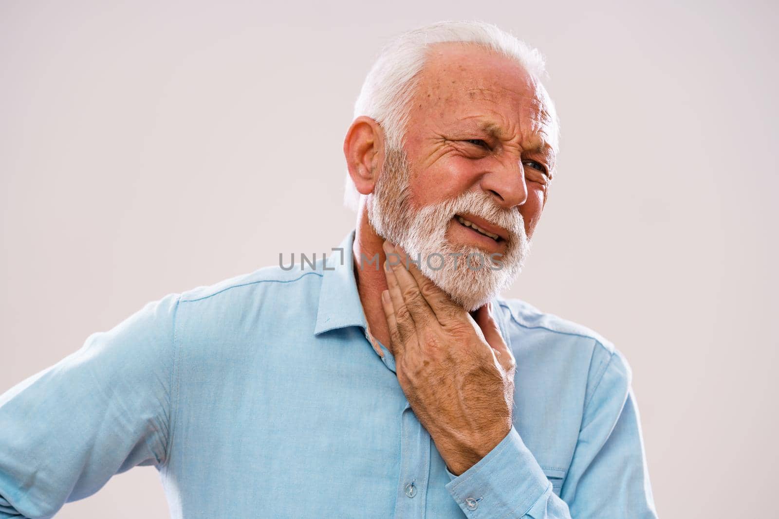 Portrait of senior man who is having pain in neck glands.