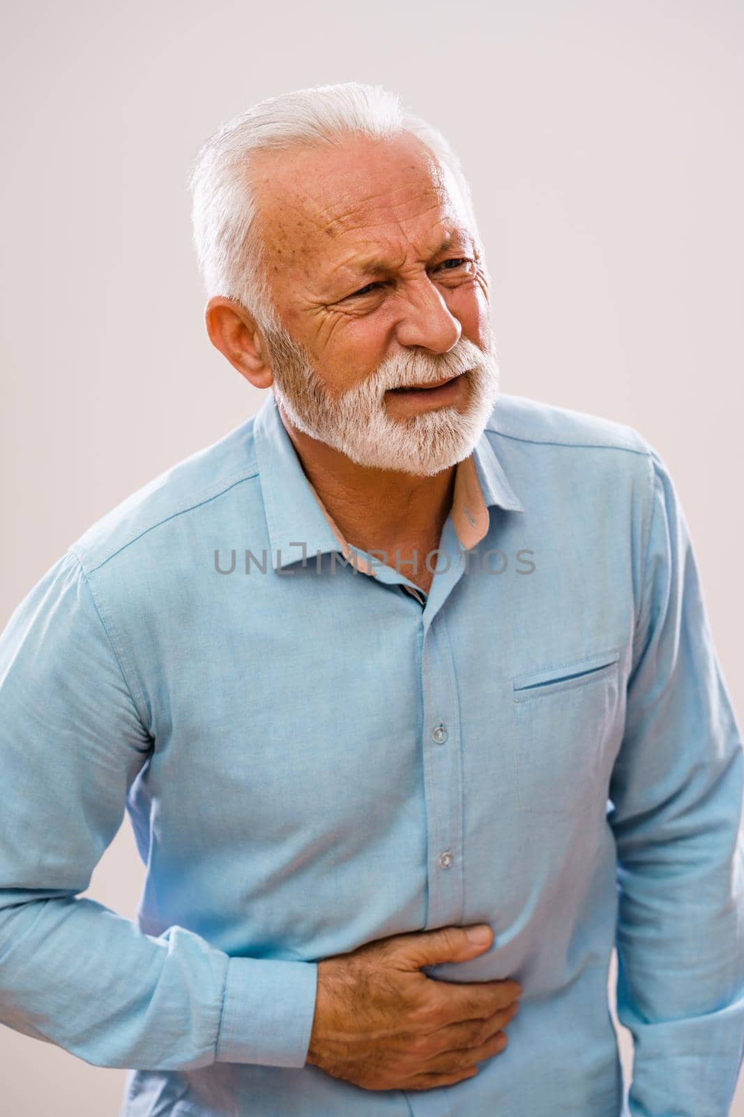 Portrait of senior man who is having pain in stomach.