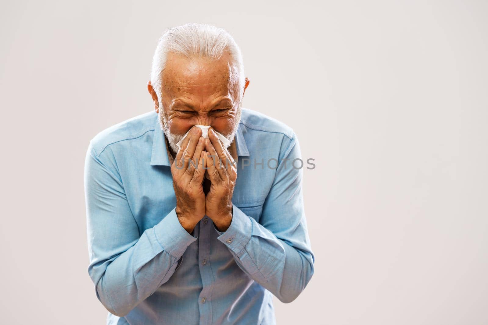 Portrait of senior man who is blowing nose.