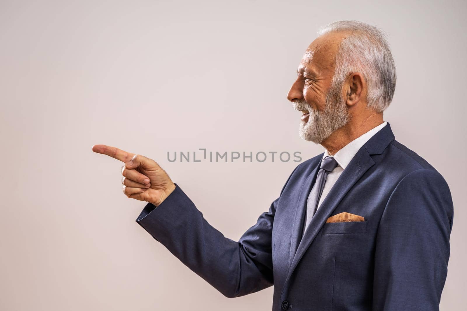 Portrait of happy senior businessman who is pointing at advertisement.
