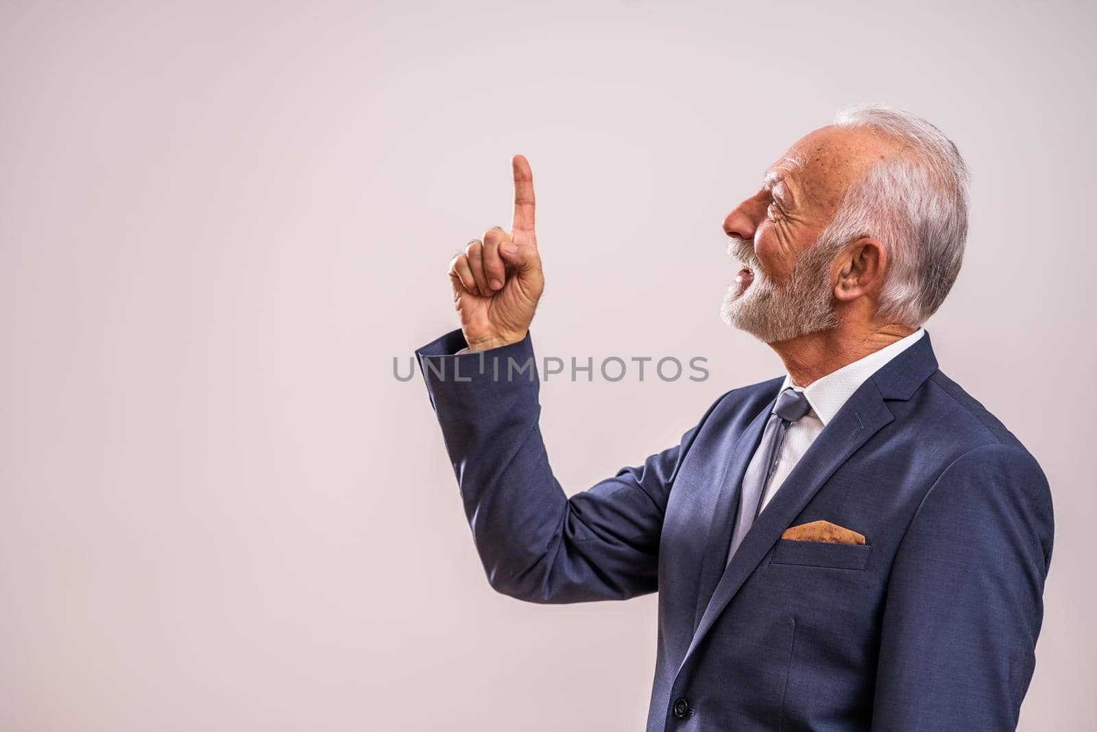 Portrait of happy senior businessman who is pointing at advertisement.