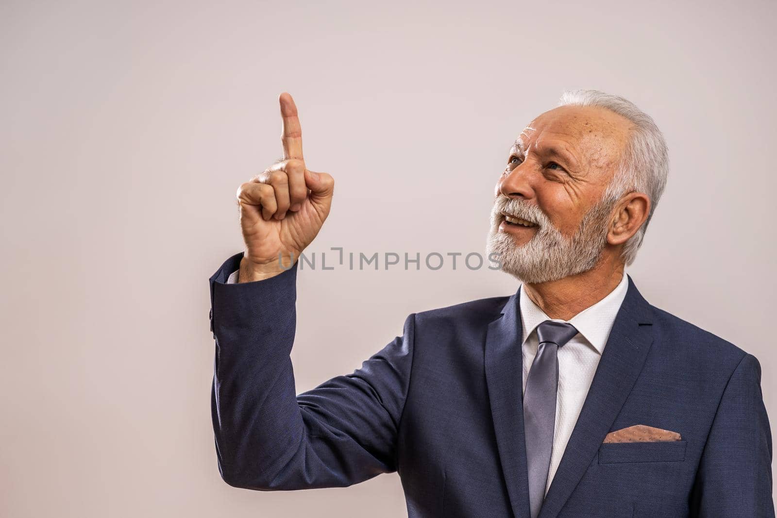 Portrait of happy senior businessman who is pointing at advertisement.