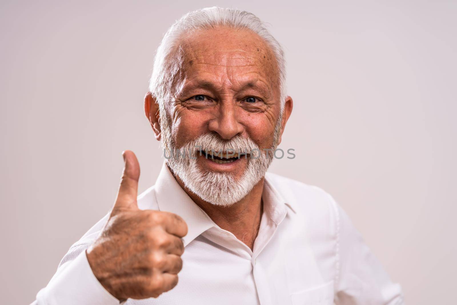 Portrait of cheerful senior man who is showing thumb up.