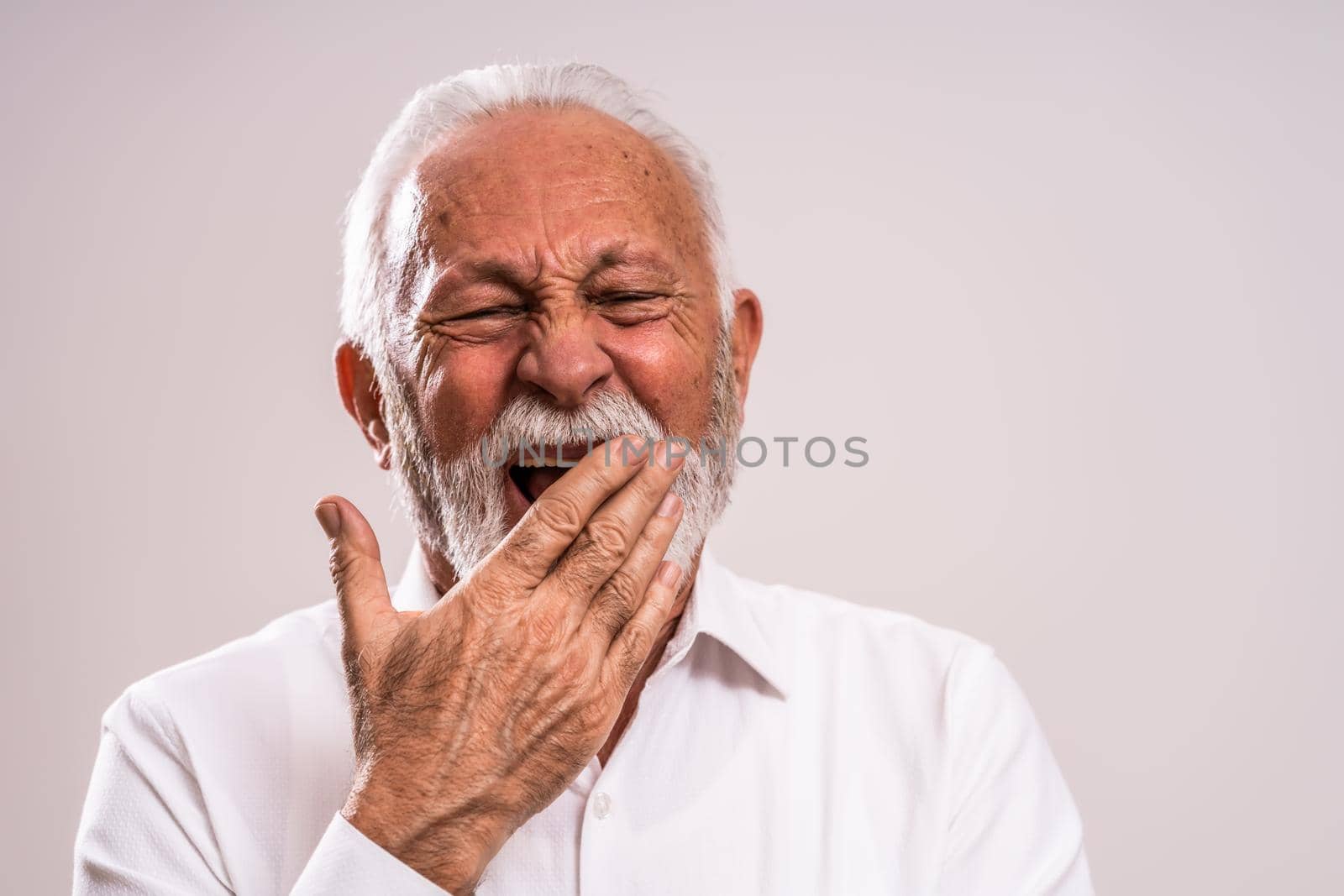 Portrait of tired senior man who yawns.