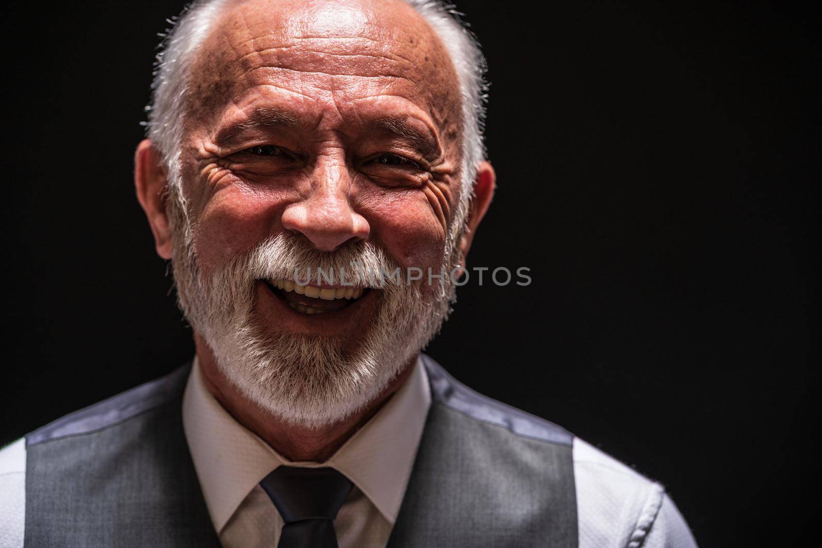 Portrait of cheerful senior man on black background.