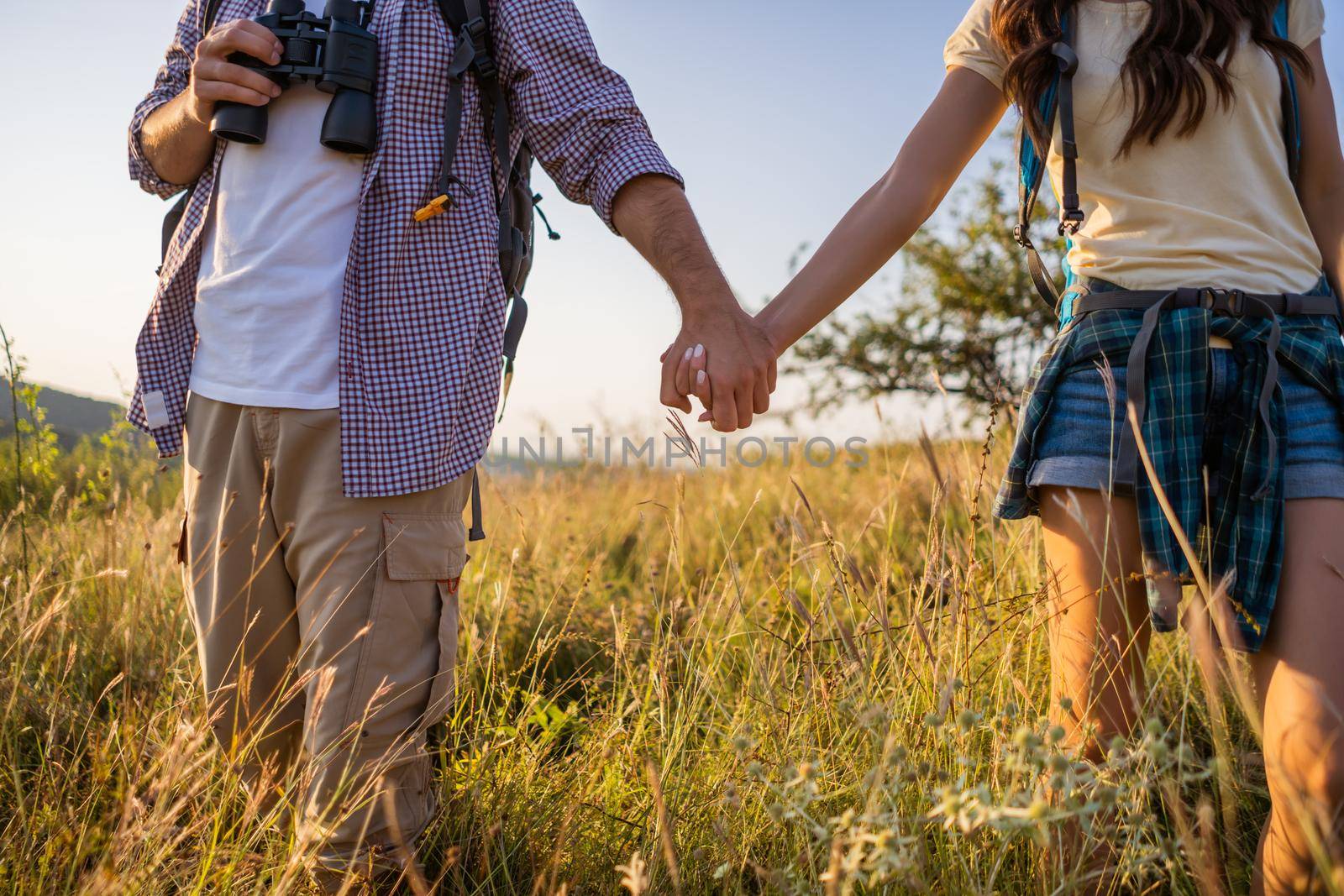 Close up of happy couple holding hands while hiking in mountain.