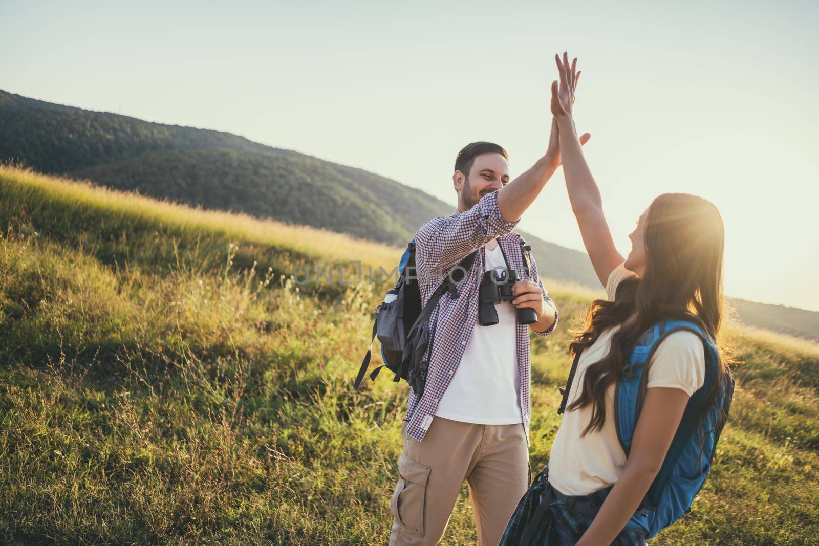 Happy couple is hiking in mountain. They are excited.