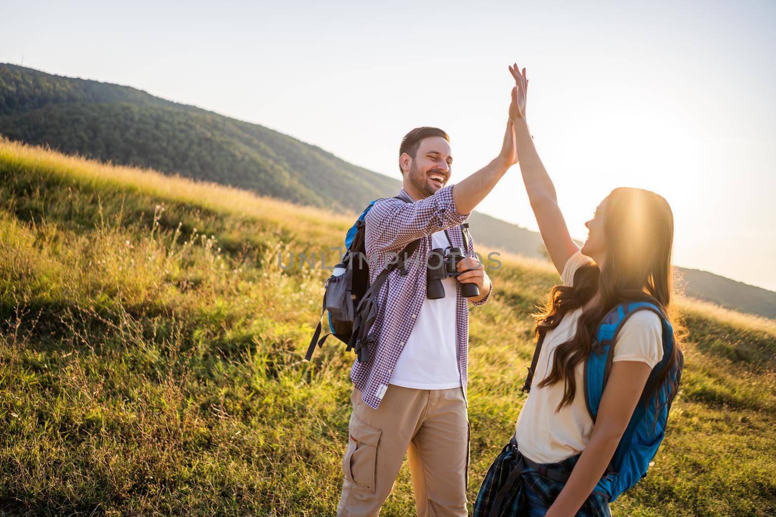 Happy couple is hiking in mountain. They are excited.