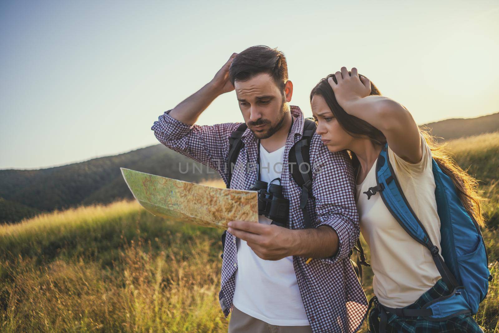 Couple is hiking in mountain. They are looking at map.