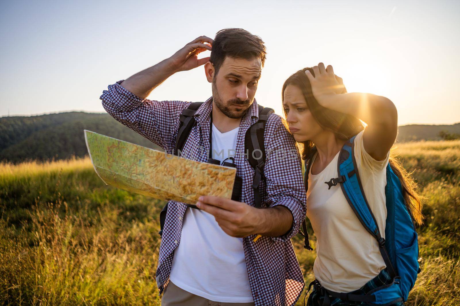 Couple is hiking in mountain. They are looking at map.