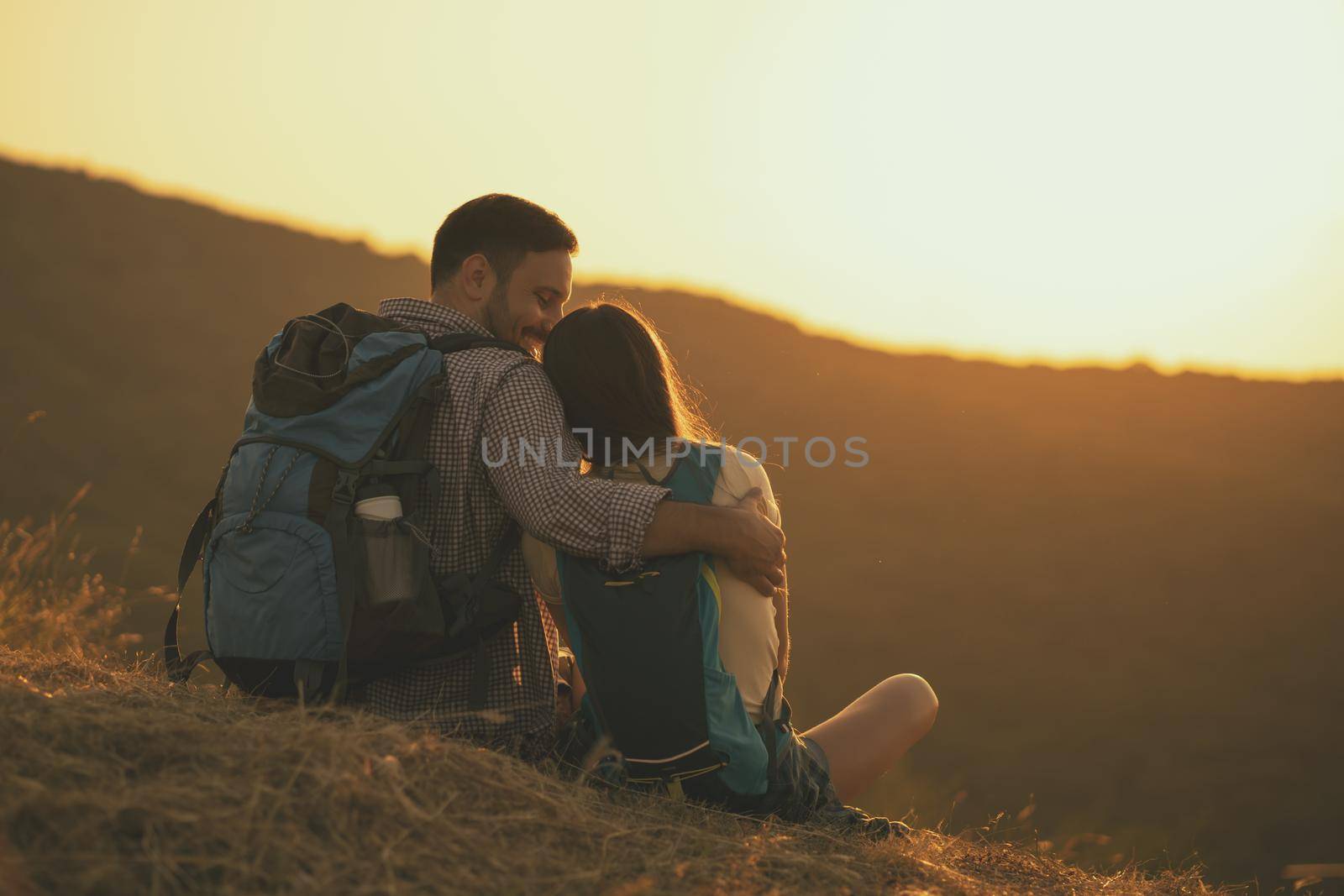 Young happy couple is hiking in mountain and enjoying sunset.