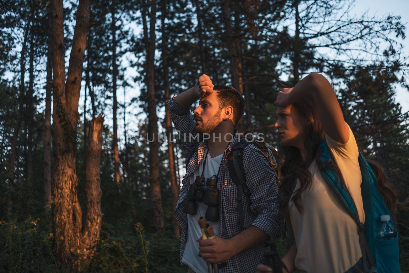 Young couple is hiking in forest. They are tired.
