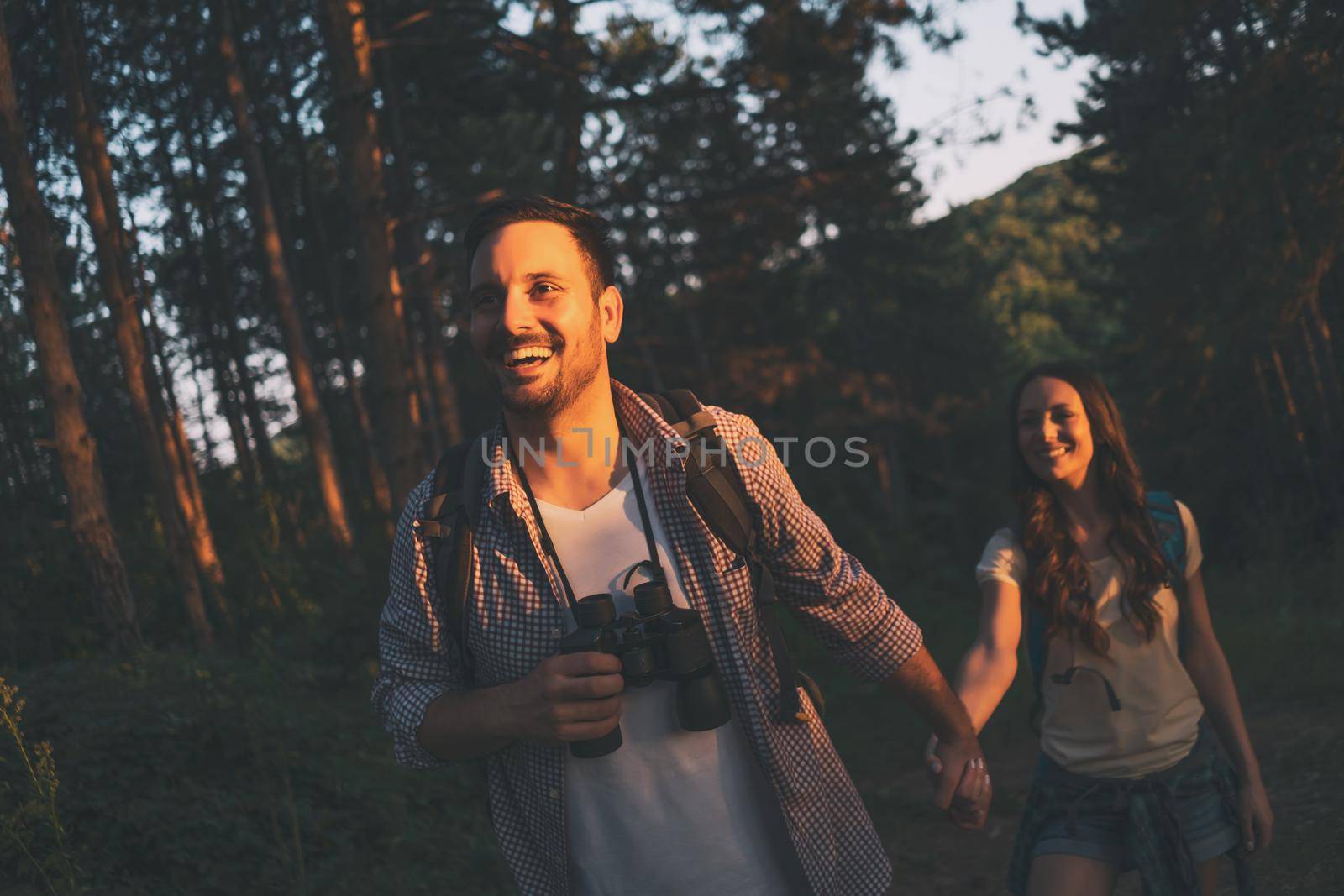 Happy couple is hiking in forest in summertime.