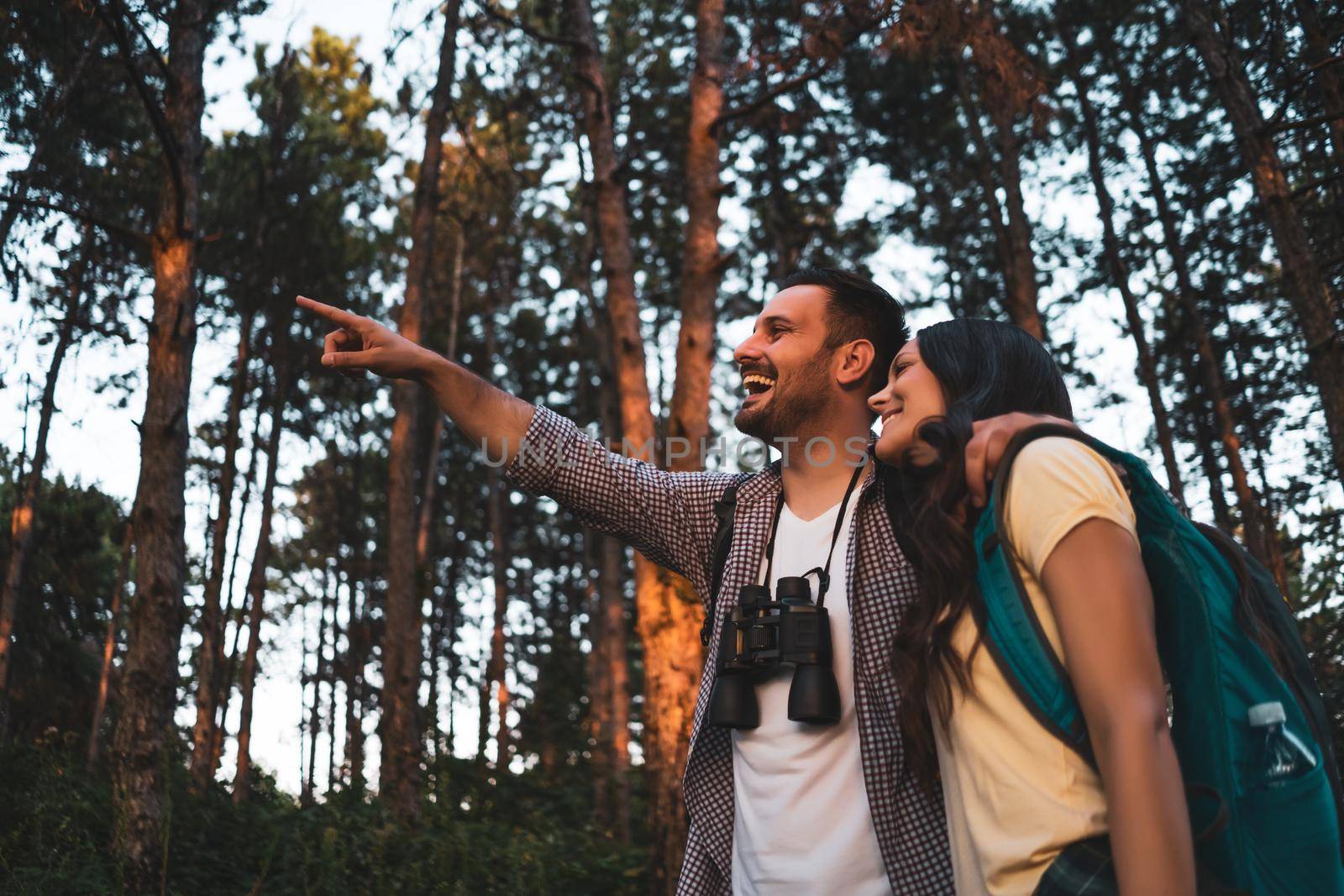 Happy couple is hiking in forest in summertime.