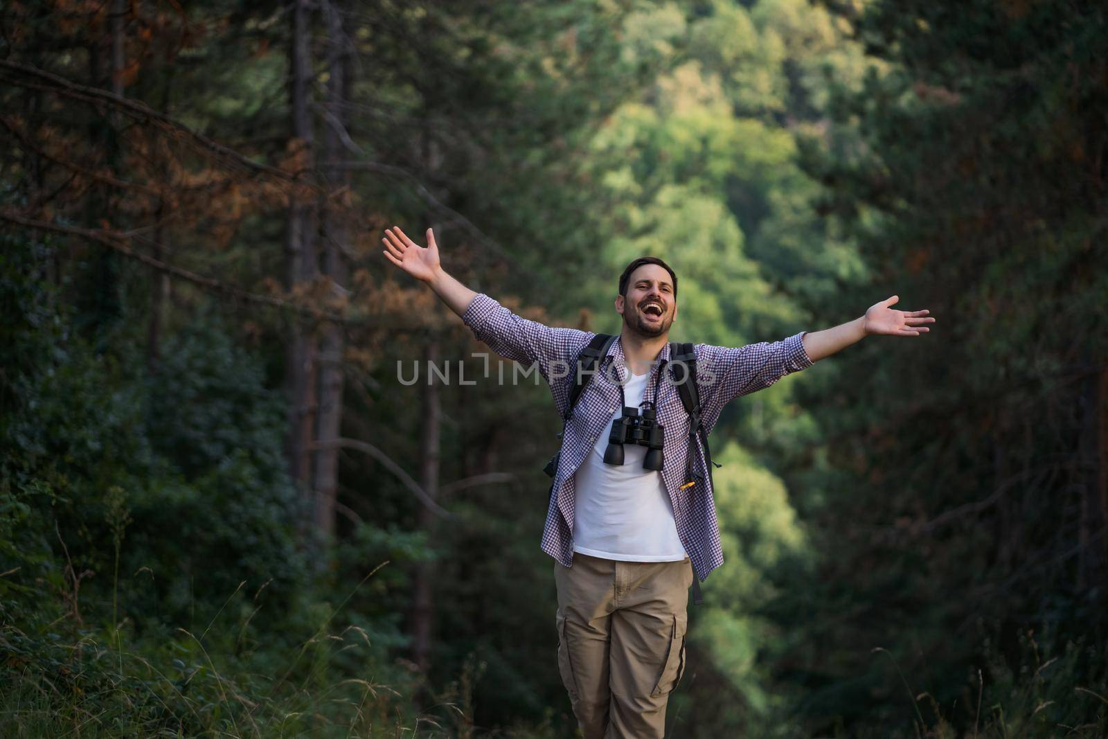 Happy adult man is hiking in forest.