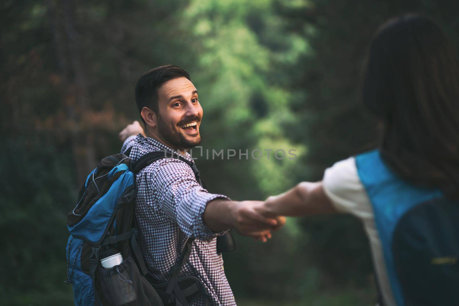 Happy couple is hiking in forest.