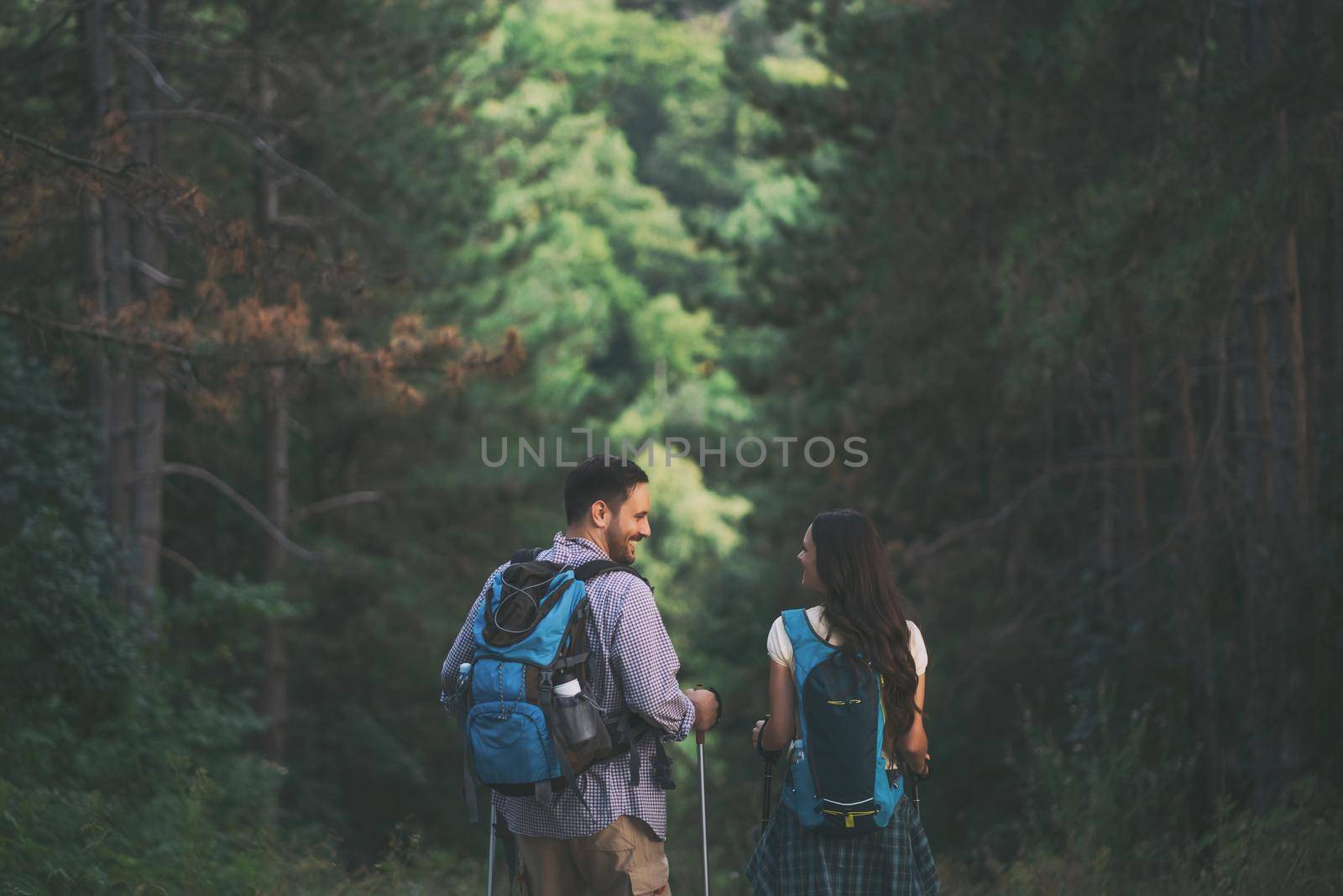 Happy couple is hiking in forest.