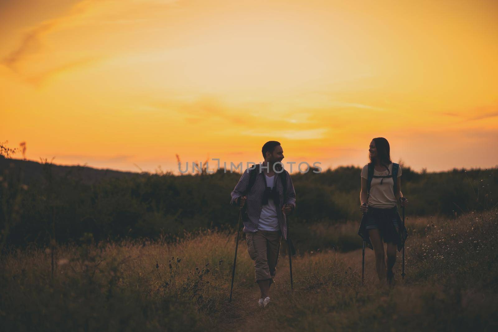 Young couple is hiking in mountain in sunset.