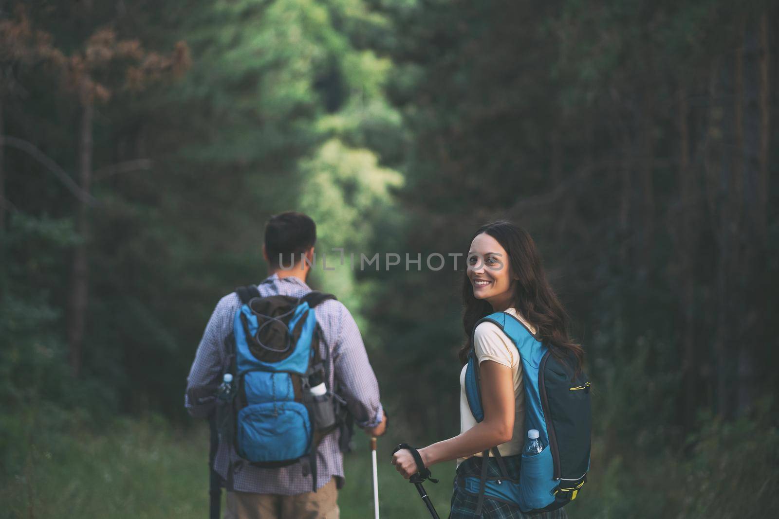 Happy couple is hiking in forest.
