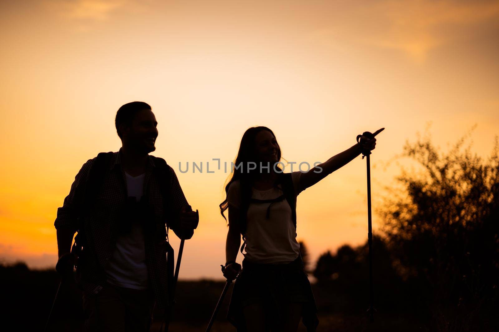 Happy couple is hiking in mountain in sunset.